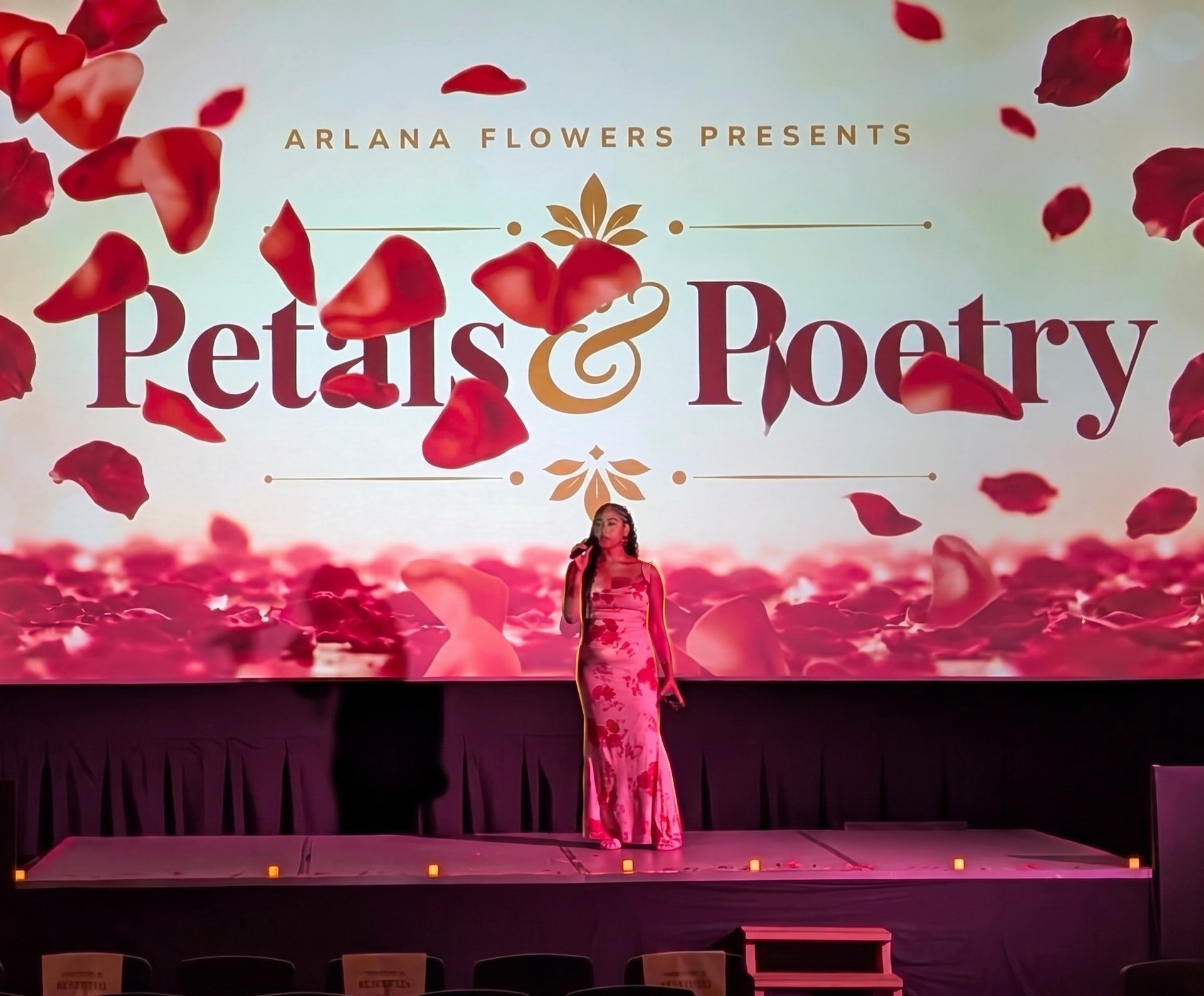 Arlana Flowers presenting Petals & Poetry on stage with rose petals falling